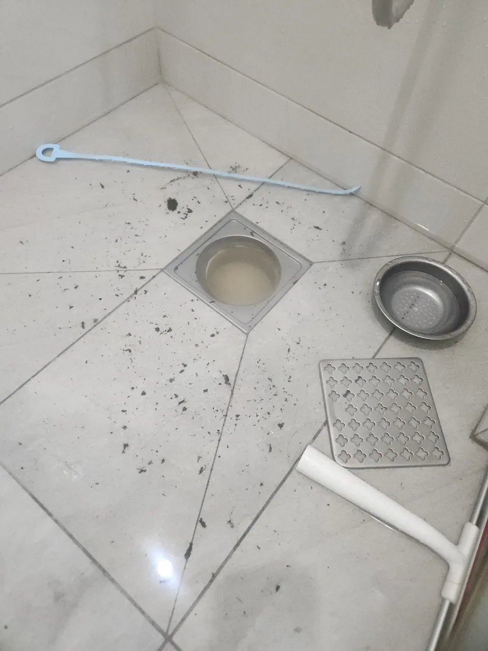 덮개를 들어낸 샤워실 배수구 주변의 머리카락 찌꺼기